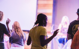 Woman with a yellow shirt worshipping in a church building