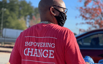 Person as seen from behind with a red shirt that has the text “empowering change