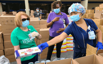 Volunteers with masks handing out items to those in their local communities who are in need